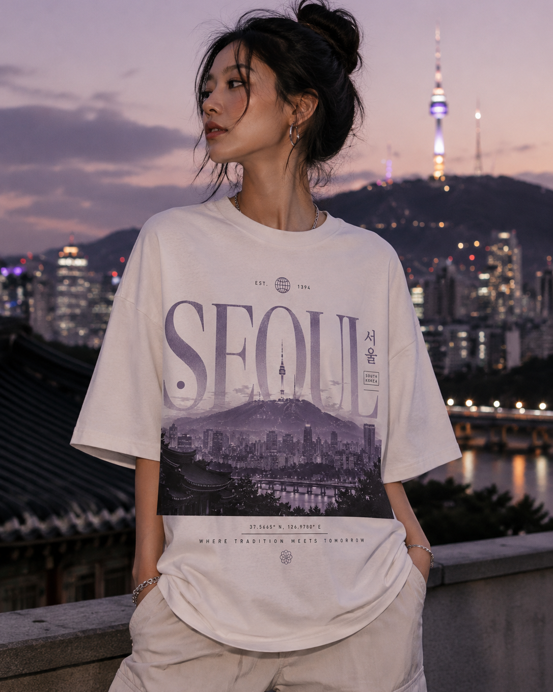 Person wearing a 'Seoul' t-shirt with a cityscape design, standing against a backdrop of the Seoul Tower and skyline.