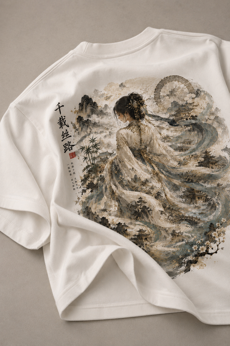A white short-sleeve T-shirt laid flat on a neutral gray background, featuring a large back print of a traditional Chinese-style watercolor painting with a woman in flowing robes, mountains, trees, and vertical black calligraphy.