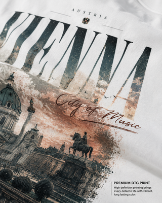 Close-up of a white T-shirt with a large Vienna cityscape graphic and the words 'AUSTRIA' and 'City of Music' printed on it. Text in the lower right reads 'PREMIUM DTG PRINT' with descriptive copy.