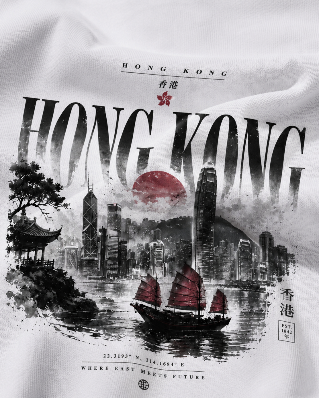 A close-up of a white fabric surface printed with a Hong Kong cityscape graphic. The design includes large black 'HONG KONG' text, a red sun, black-and-white skyscrapers, a red-raked junk boat on water, and small Chinese characters.